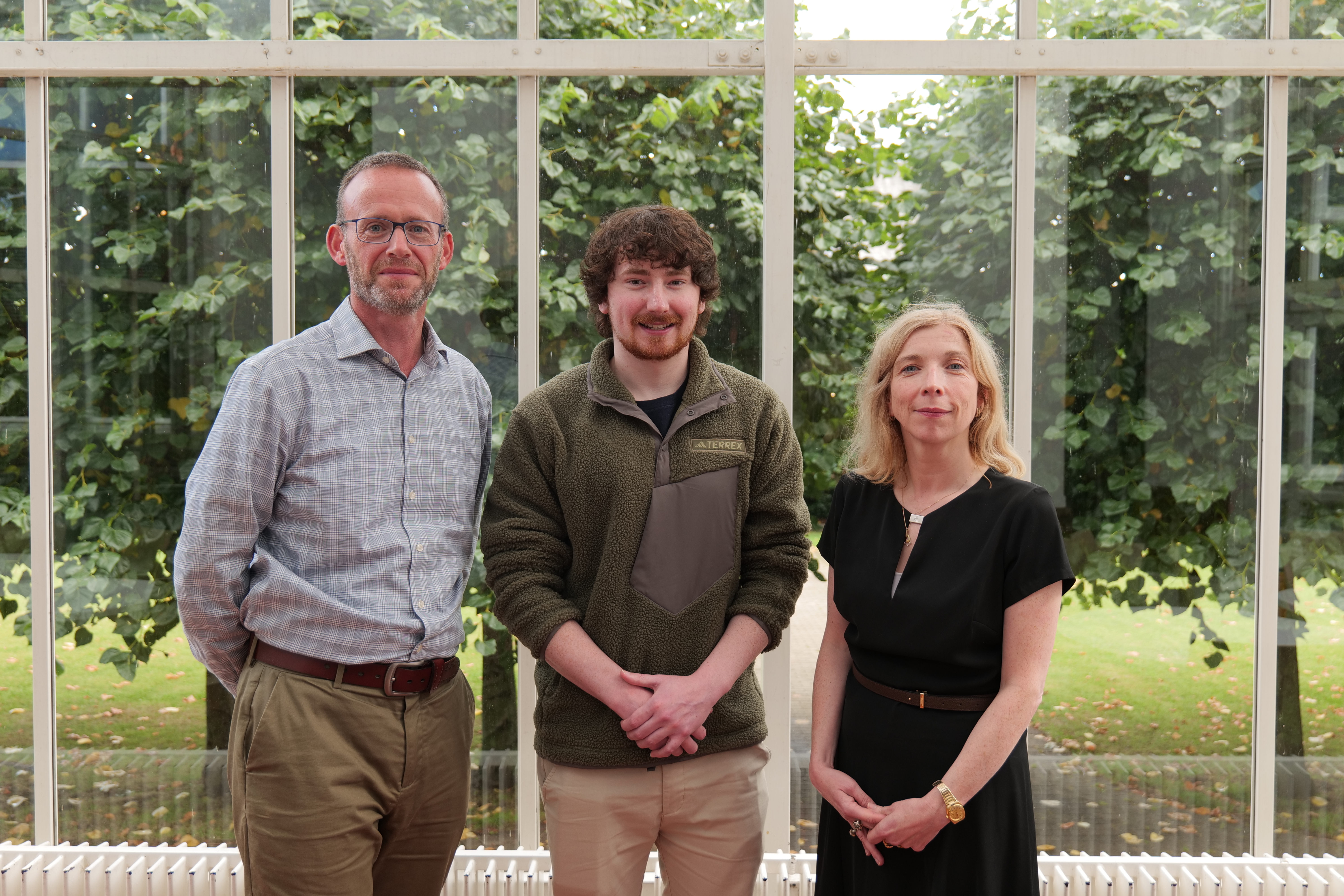 3 people standing against a window.